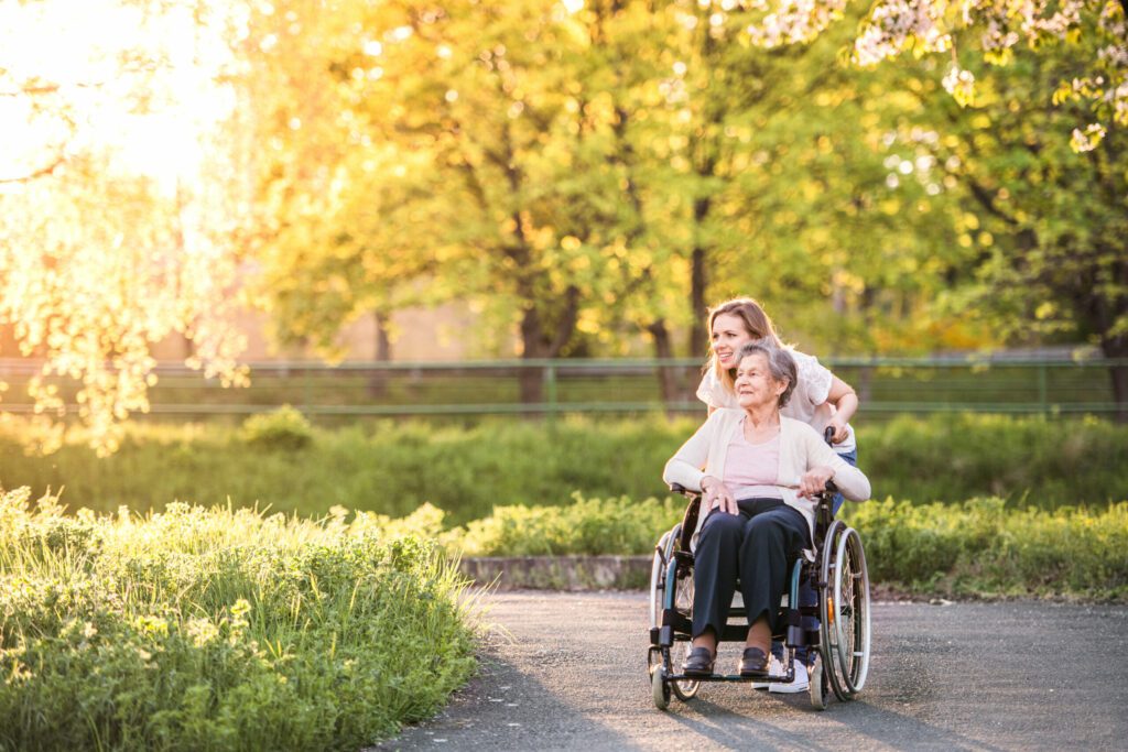 The Heritage of Green Hills | Elderly grandmother in wheelchair with granddaughter in spring nature.